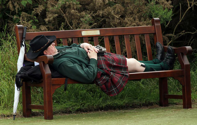 Este espectador escocs duerme en un banco del campo de golf de St. Andrews en Escocia, en el trascurso de la tercera jornada del British Open.