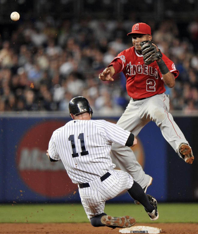 El shortstop Erick Aybar de Los Angeles Angels, salta sobre la carrera del bateador de los yankees Brett Gardner, para evitar que le destroce las piernas, en el partido correspondiente a la Liga Profesional de Baseball Americana (MLB).