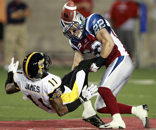 Drisan James, de los Hamilton Tiger-Cats, recibe un duro golpe de un rival durante un partido de la CFL football.