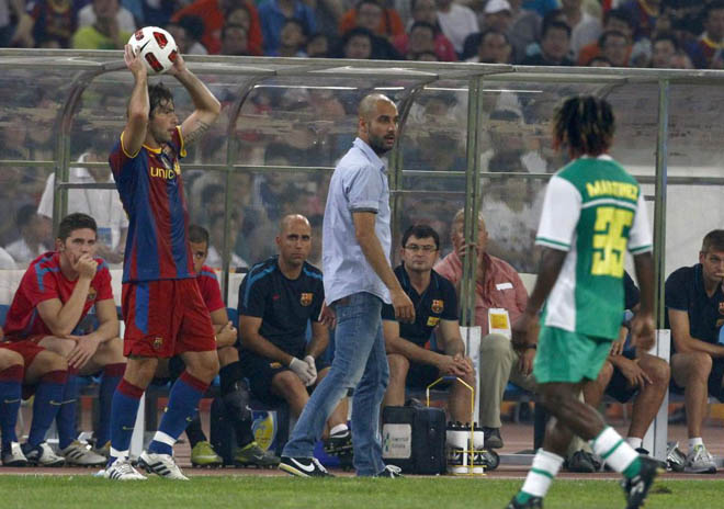 El tcnico del Barcelona, Pep Guardiola, no pierde detalle, desde el banquillo, de los pormenores del partido amistoso que disputa el Bara en el National Stadium de Beijing.