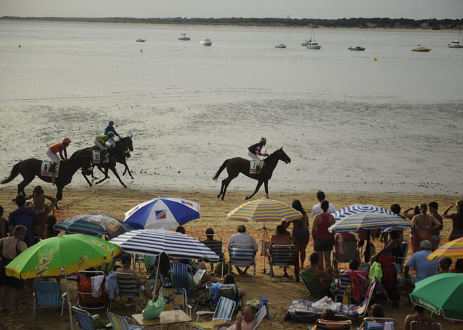 La tradicional carrera de caballos de San Lcar de Barrameda se celebra en la playa. Muchos baistas pueden disfrutar de esta emocionante carrera mientras se meten un buen chapuzn.