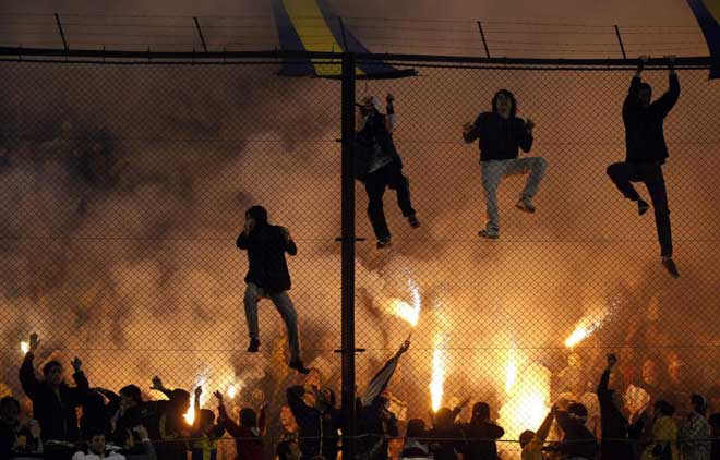 Aficionados de Boca Juniors trepando por las vallas y encendiendo bengalas durante el partido que enfrentó a su equipo contra el Colón de Santa Fe.
