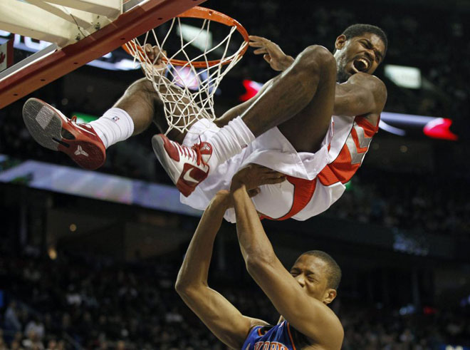Amir Johnson, jugador de los Raptors, machacando el aro de los Knicks ante la mirada de Anthony Randolph.