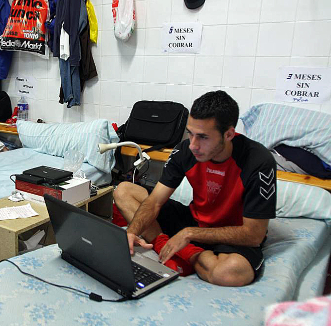 Un jugador del Algericas maneja su ordenador tras el encierro de su equipo en los vestuarios de su estadio.