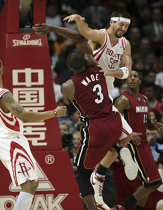 Dwyane Wade, de los Miami Heat, y Brad Miller, de los Houston Rockets, pugnan durante el choque que enfrentó a ambos conjuntos la pasada madrugada.