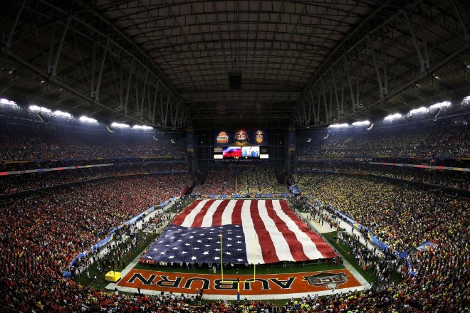 Una bandera americana cubre todo el terreno de juego antes del comienzo del Tostitos BCS National Championship.