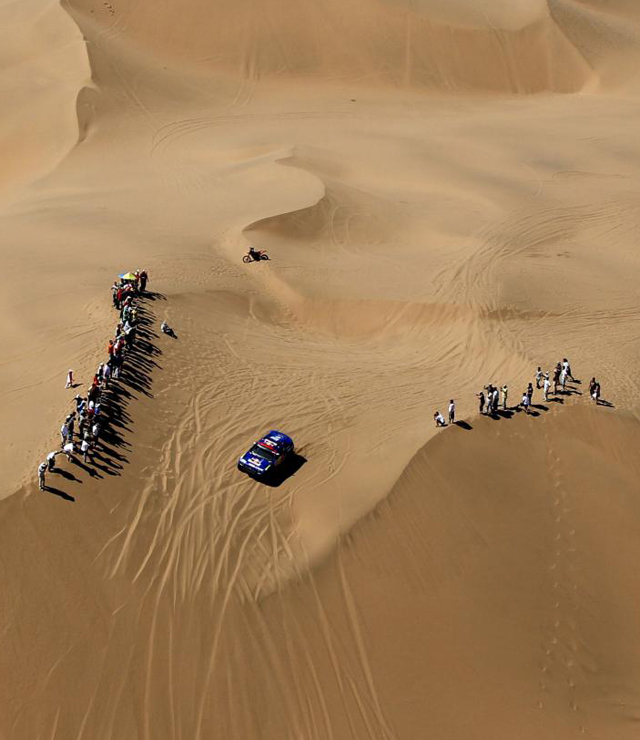 Unos cuantos aficionados seguan in situ la novena etapa del Dakar arropando a los participantes a su paso entre dos dunas.