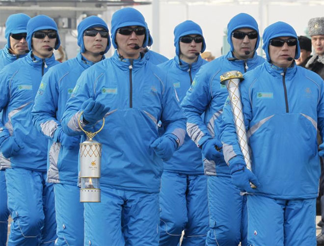 El personal de seguridad, con la llama de los Juegos Asiticos de Invierno en un relevo de la antorcha en Almaty.