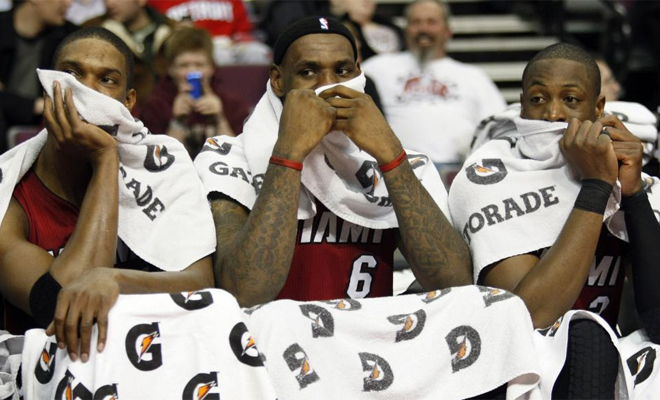 Chris Bosh, LeBron James y Dwyane Wade hablan con la boca tapada durante un momento del encuentro ante los Pistons.