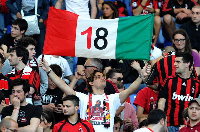 Un aficionado del Milan muestra feliz la bandera de Italia con el 18 (las ligas que lha conquistado su equipo) en el centro.