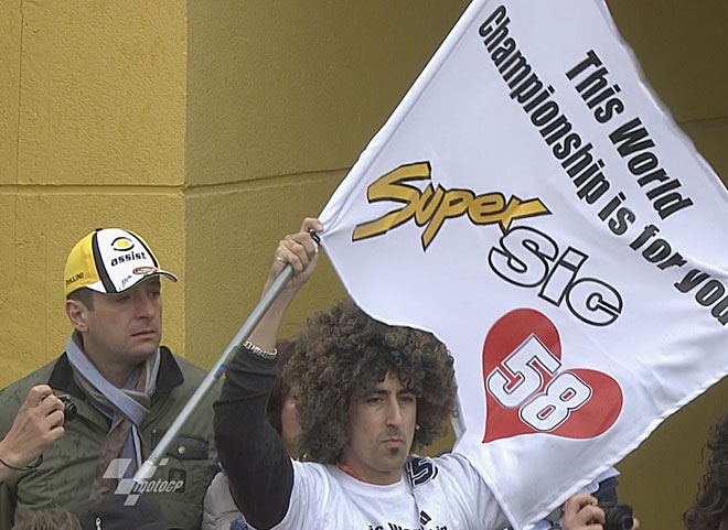 Un aficionado con una peluca a lo Simoncelli porta una bandera con el lema 'Este campeonato del mundo es para ti'.