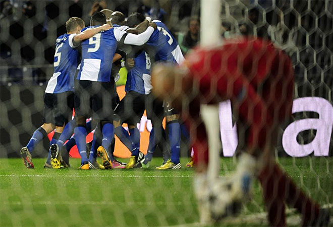 El portero argentino del Mlaga recoge la pelota de dentro de su portera mientras los jugadores del Oporto forman una pia en el fondo.