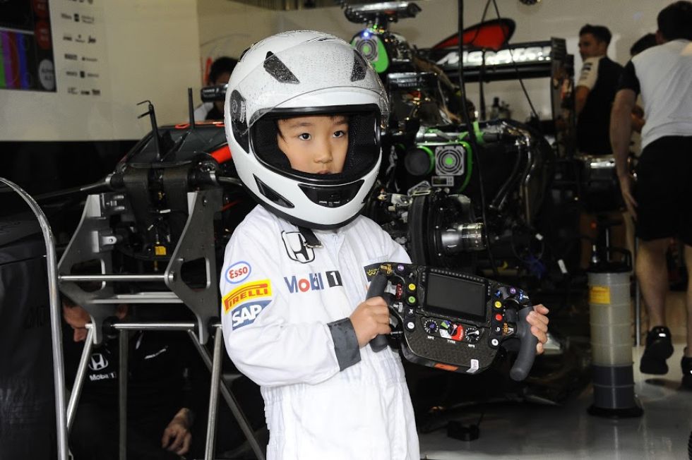 Un niño japonés, vestido con el mono y el casco de McLaren Honda.