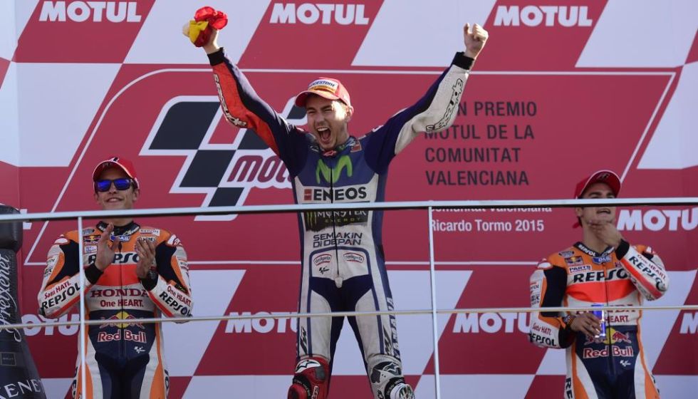 Lorenzo celebra la victoria en el podio con Mrquez y Pedrosa al fondo.