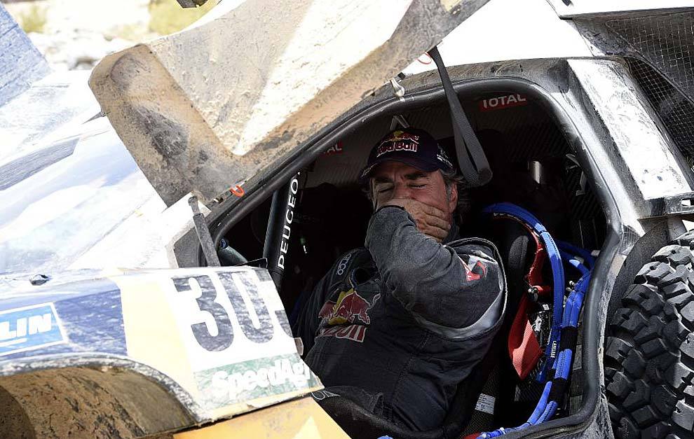 Carlos Sainz se tapa la boca dentro de su Peugeot mientras espera a...