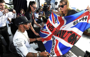 Hamilton firma una bandera britnica a una aficionada.