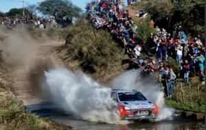 Un coche atraviesa un camino con agua en el Rally de Argentia.