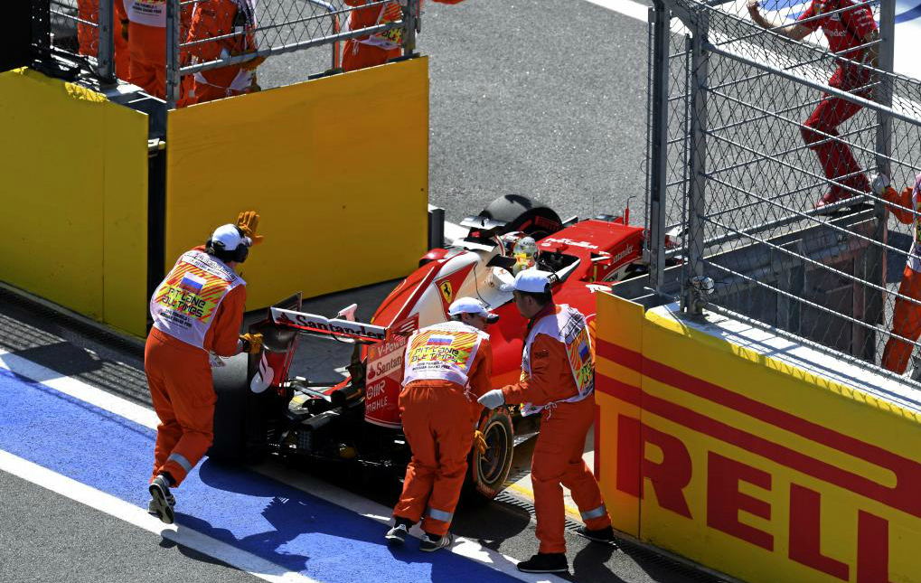 Comisarios del circuito retiran el monoplaza de Sebastian Vettel en el...