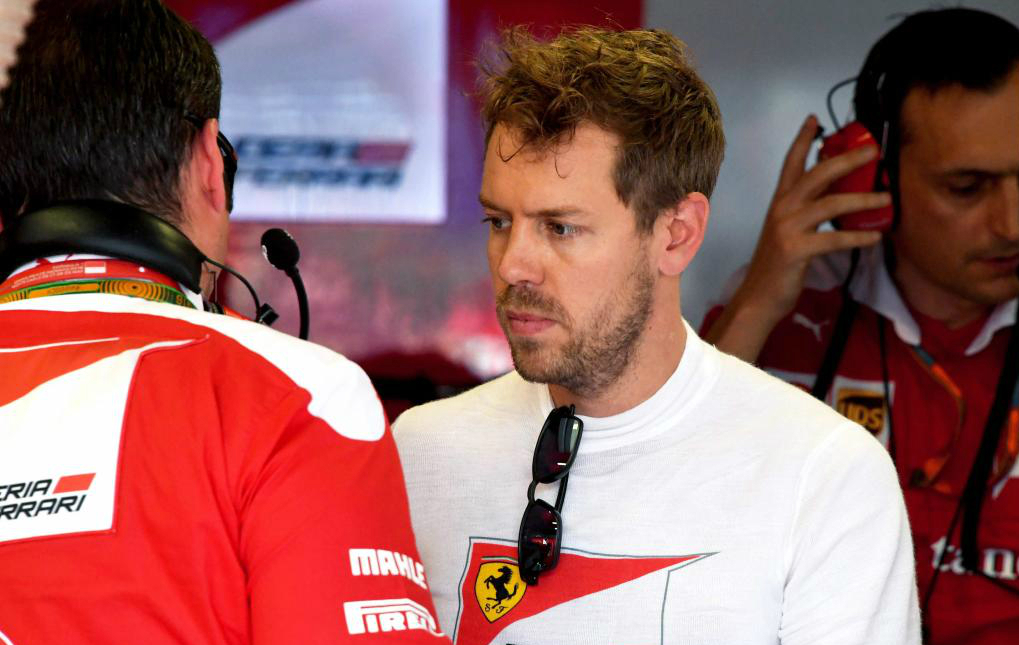 Sebastian Vettel charla con sus mecnicos en el box de Ferrari