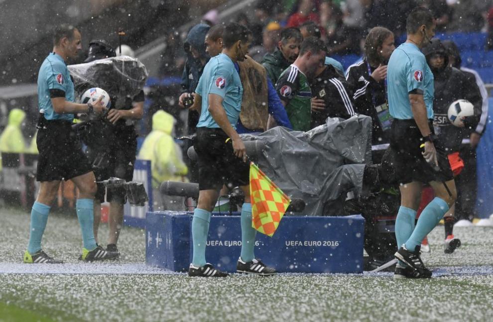 Referees leave the pitch during a hailstorm during the Euro 2016 group...