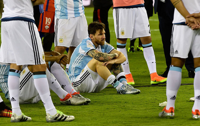 Messi mira con tristeza sentado en el csped tras perder la final...