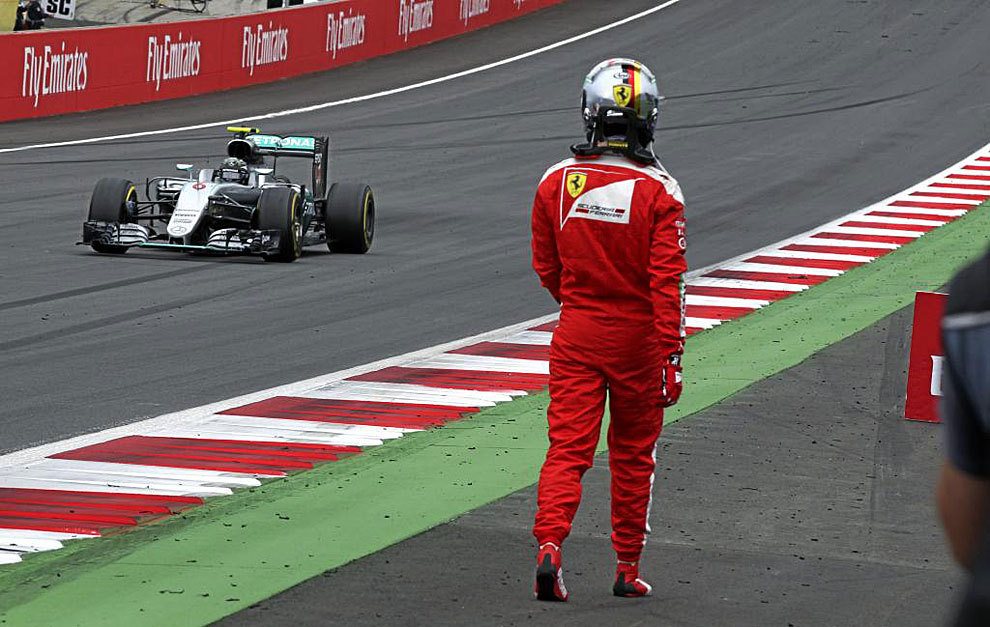Vettel regresa al box caminando tras el accidente, mientras ve pasar a...