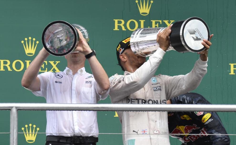Lewis Hamilton bebiendo de su trofeo en el podio