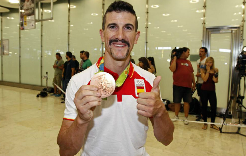Carlos Coloma ensea su bronce en su llegada a Barajas.