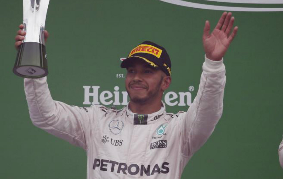 Hamilton saluda a los aficionados en el podio tras recibir el trofeo...