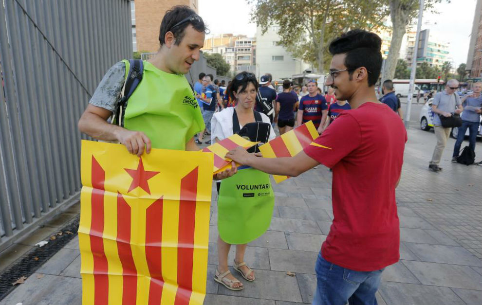 Un voluntario reparte estelades en los accesos del Camp Nou