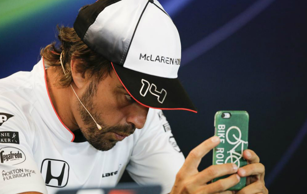 Alonso observa su smartphone durante una rueda de prensa