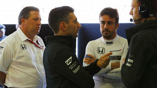 Zak Brown y Fernando Alonso escuchan a dos ingenieros de McLaren.