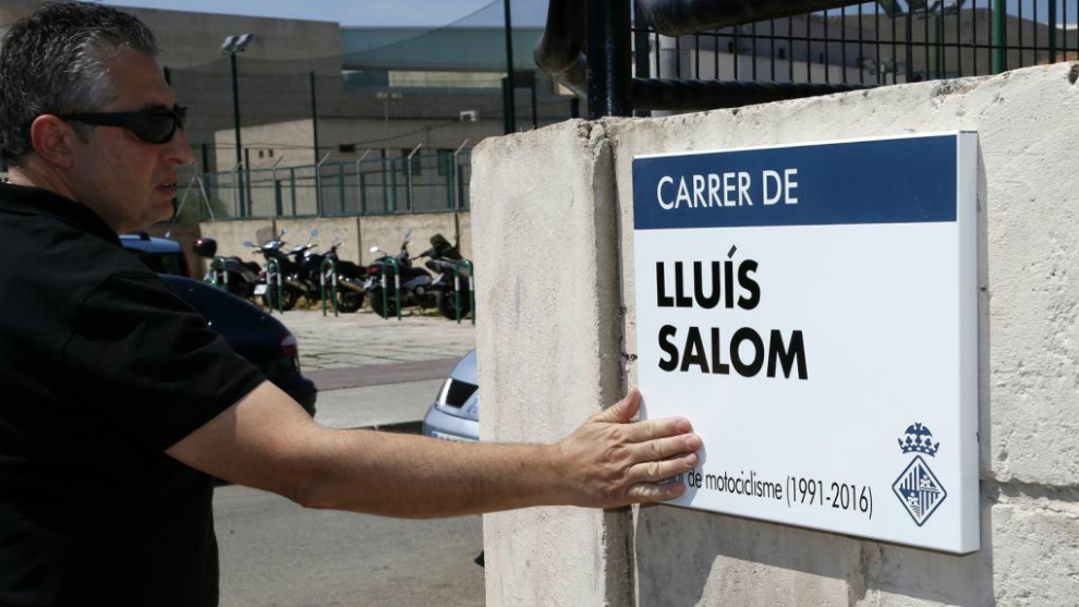 Un seguidor de Luis Salom toca la placa de la calle en homenaje al piloto fallecido en Palma de Mallorca.