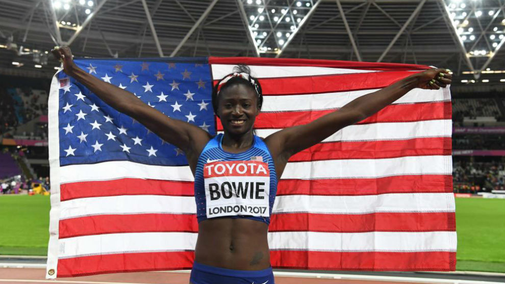 Tori Bowie celebra su triunfo con la bandera estadounidense.