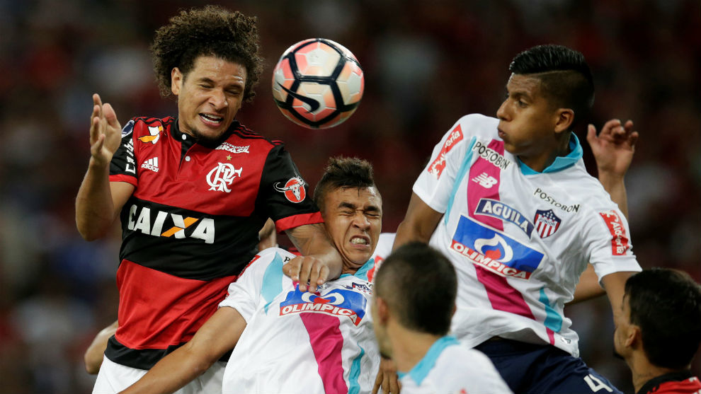 Willian Arao, de Flamengo, trata de cabecear ante la poblada defensa...