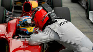 Schumacher se acerca a charlar con Alonso, en el parque cerrado del GP...