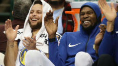 Stephen Curry y Kevin Durant sonren y aplauden durante un partido