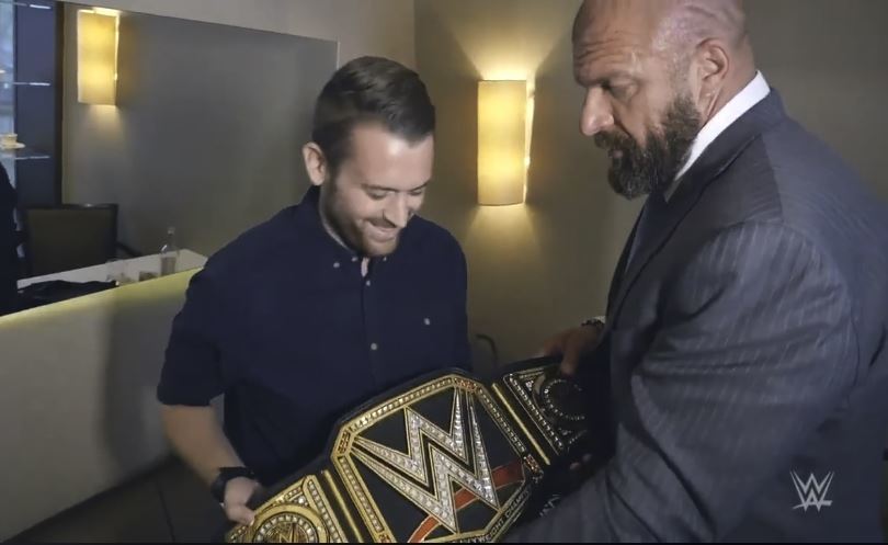 Charlie junto al luchador de la WWE, Triple H, que le entrega un...
