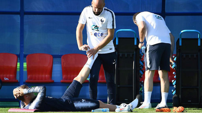 Griezmann streches with medical staff during a training session.