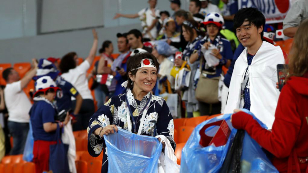 Aficionados japoneses recogiendo la basura tras el partido.