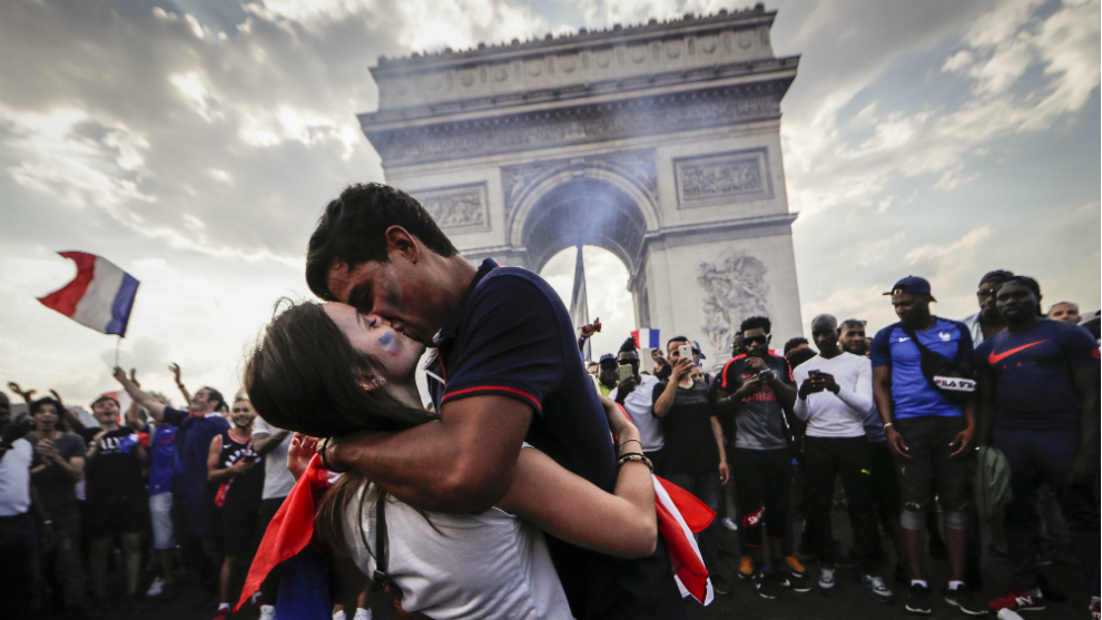 Dos aficionados franceses se besan frente al Arco del Triunfo de París