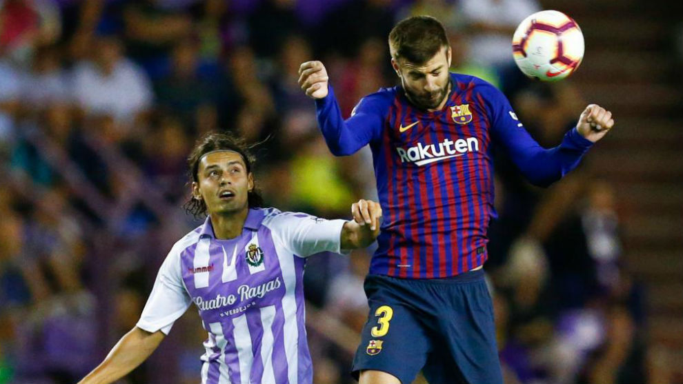 Pique heads the ball beside Real Valladolid&apos;s Croatian forward Duje...