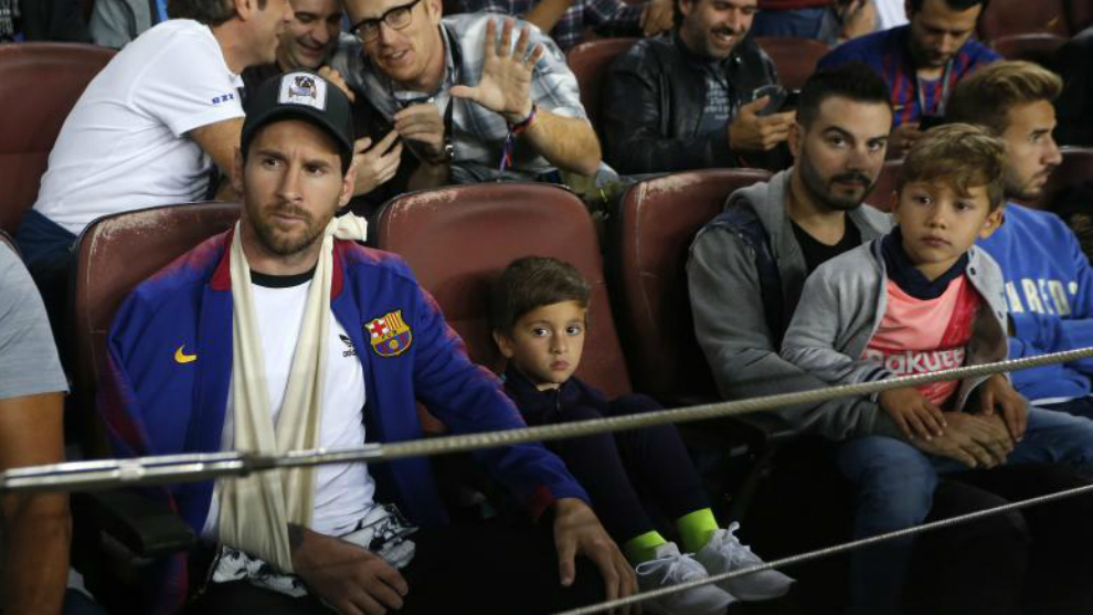 Leo Messi, con su hijo Thiago, asiste al Bara-Inter con el brazo...