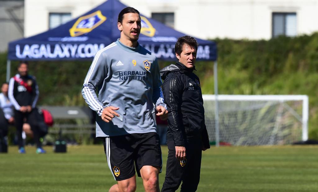 Guillermo Barros Schelotto, head coach of the LA Galaxy of the MLS watches his players during a training session as Galaxy forward Zlatan <HIT>Ibrahimovic</HIT> runs past on February 22, 2019 in Carson, California. - From Buenos Aires to Los Angeles, without stops. From Boca to Galaxy, without safety net. Losing the final of the Libertadores against his archrival River to try to resurrect the most honored franchise in MLS history, Guillermo Barros Schelotto has never been afraid of the challenges. (Photo by Frederic J. BROWN / AFP)