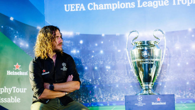Carles Puyol posing alongside the Champions League trophy