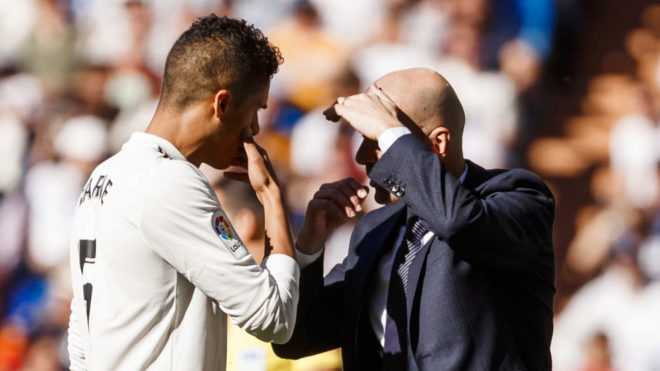 Zidane passes on instructions to Varane on the sidelines.