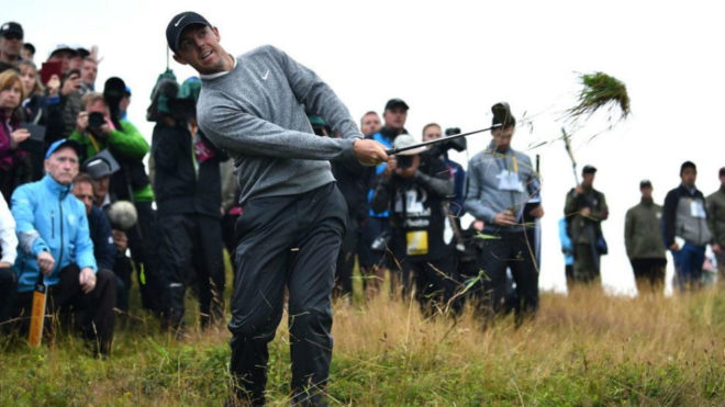 Rory McIlroy juega desde la hierba alta un golpe.