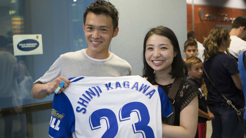 Una pareja de japoneses posa con la camiseta de Kagawa recin...