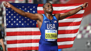 Christian Coleman posa con la bandera de Estados Unidos tras ganar la...