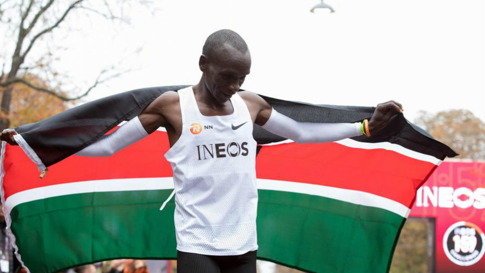 Kipchoge festeja con la bandera de su país el reto de bajar de dos horas en maratón